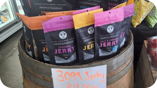 Packs of 3099 Jerky in Teriyaki, Garlic, and Salt & Vinegar flavours displayed in a wooden barrel.