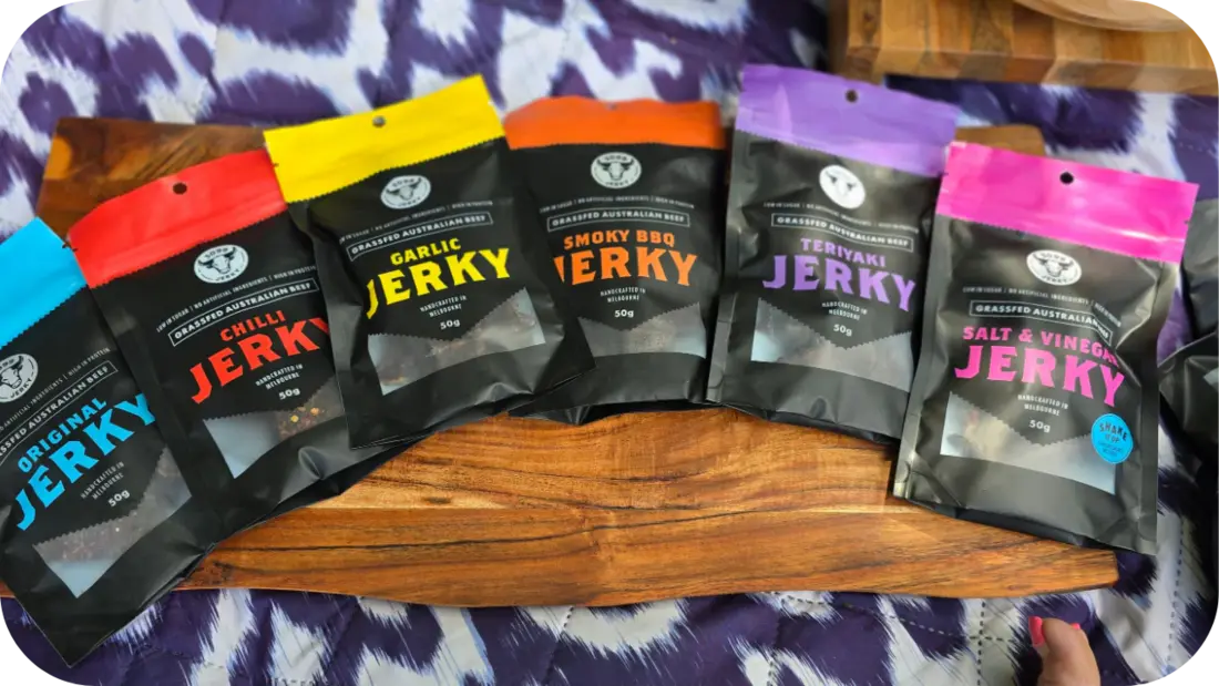 A row of 3099 Jerky packs in flavours like Original, Chilli, Garlic, Smoky BBQ, Teriyaki, and Salt &amp; Vinegar on display.