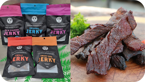  Display of 3099 Jerky packs in flavours like Salt & Vinegar, Chilli, and Smoky BBQ beside a wooden board of sliced jerky.